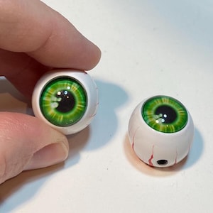 May include: Two green and black plastic eyeballs with white sclera and red veins. The eyeballs are about 1 inch in diameter.