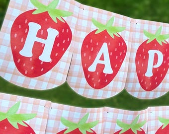 May include: A red and green strawberry banner with the word "Happy" spelled out on it. The banner is made of paper and has a gingham pattern.