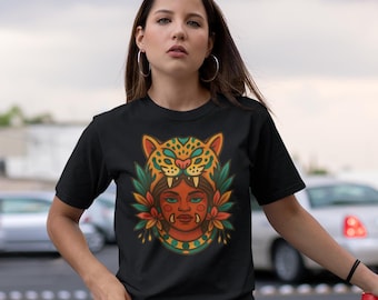 May include: Black t-shirt featuring a colorful graphic of a woman wearing a jaguar headdress. The design includes orange, green, and yellow accents. The text "IKACHI ART Love for Our Roots" is in the upper left corner.