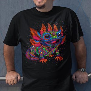 May include: Black t-shirt with a colourful axolotl design. The axolotl is decorated with intricate patterns in blue, orange, green, and pink. The shirt has a crew neck and short sleeves. The design includes the text "IncanArt Love for Our Roots".