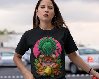 May include: Black t-shirt featuring a colorful graphic of a green-skinned figure with a headdress, set against a pink circle. The figure is seated with a brown object in its hands. The shirt has the text "IKACHI ART Love for Our Roots" at the top.