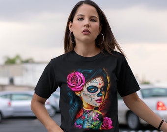 May include: A woman wearing a black t-shirt with a colorful graphic of a woman with a sugar skull face and flowers. The graphic is a Day of the Dead inspired design.