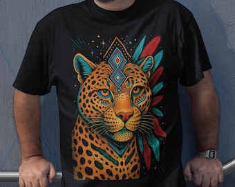 May include: Black t-shirt featuring a detailed illustration of a jaguar with geometric patterns and colorful feathers. The jaguar has orange, blue, and teal accents. The shirt has the text "Ixachiart Love for Our Roots" in the upper left corner.