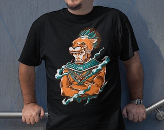 May include: A black t-shirt with a graphic print of a stylized orange and green jaguar warrior with a feathered headdress. The warrior is wearing a necklace and has a fierce expression.