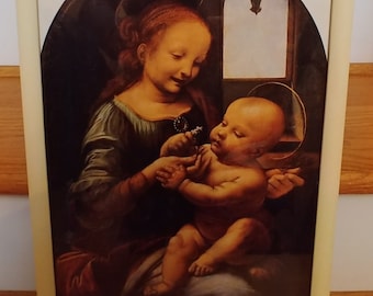 May include: A framed print of a painting depicting the Virgin Mary holding a baby Jesus. The painting is in a traditional style with a dark background and a halo around the Virgin Mary's head. The baby Jesus is wearing a white cloth and is holding a flower.