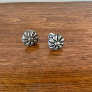 May include: Two silver metal cabinet knobs with a flower design.