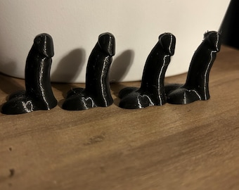 May include: Four small, black, 3D printed objects in a row on a wooden surface.