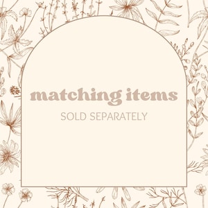 Puede incluir: Un fondo beige con un estampado floral en tonos marrones. Una forma de arco beige contiene el texto "matching items" y "SOLD SEPARATELY" en marr&oacute;n.