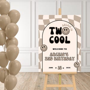 Puede incluir: Un letrero de bienvenida para una fiesta de cumpleaños sobre un caballete. El letrero tiene un fondo a cuadros beige y blanco con las palabras "TWO COOL" en negro. El letrero dice "Welcome to Archie's 2nd Birthday" y la fecha "15 de junio de 2026". Globos beige en el fondo.