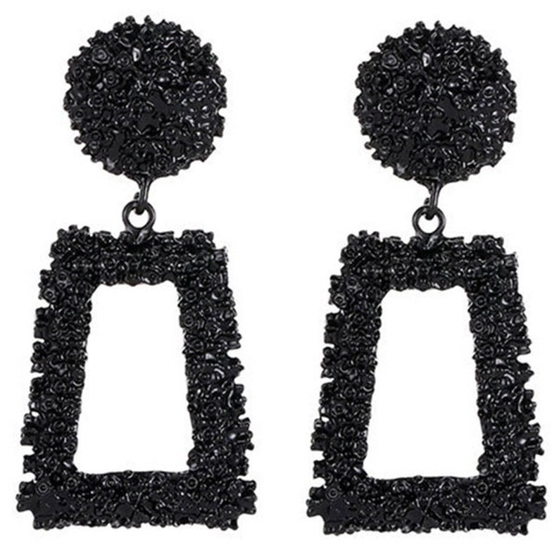 May include: A pair of black geometric earrings with a textured finish. The earrings are shaped like a rectangle with a smaller rectangle cut out in the center.