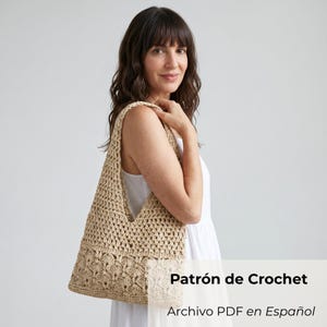 Puede incluir: Un bolso de crochet en color beige con un patrón calado texturizado en la parte superior y un diseño de puntos densos e intrincados inspirados en flores en la parte inferior. El bolso incluye el texto Patrón de Crochet Archivo PDF en Español.
