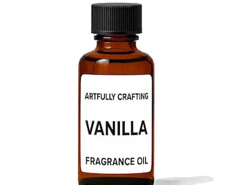 May include: A small amber glass bottle with a black screw-top cap. The white rectangular label features the black text ARTFULLY CRAFTING, VANILLA, and FRAGRANCE OIL. The bottle contains a liquid substance and is designed for storage and dispensing.