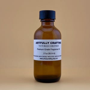 May include: A brown glass bottle with a black lid, labeled "Artfully Crafting Victorian Christmas Premium Grade Fragrance Oil 2 fl oz (59.14 ml)".