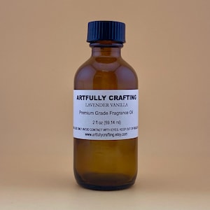 May include: A brown glass bottle with a black cap, labeled "Artfully Crafting Lavender Vanilla Premium Grade Fragrance Oil 2 fl oz (59.14 ml)".