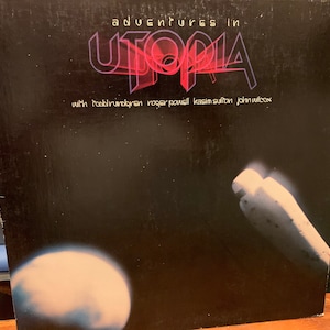 May include: A black vinyl record album cover with the title "Adventures in Utopia" in pink and purple lettering. The album features the band Utopia with Todd Rundgren, Roger Powell, Kasim Sulton, and John Wilcox.
