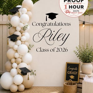 Może przedstawiać: Tło na przyjęcie z okazji ukończenia szkoły z kremowym łukiem z napisem "Gratulacje Riley Klasa 2026". Girlanda balonowa w odcieniach bieli i beżu znajduje się po lewej stronie. Mały znak głosi "Gratulacje Absolwencie!" z czapką absolwenta.