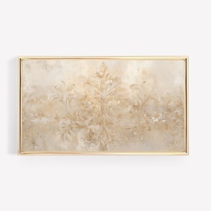 May include: A framed wall art print with a gold frame. The print features a beige background with a gold, intricate, symmetrical design.