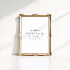 May include: A gold-framed print with a white background and black text that reads "Baskets full of joy, eggs full of surprises, and hearts full of love".