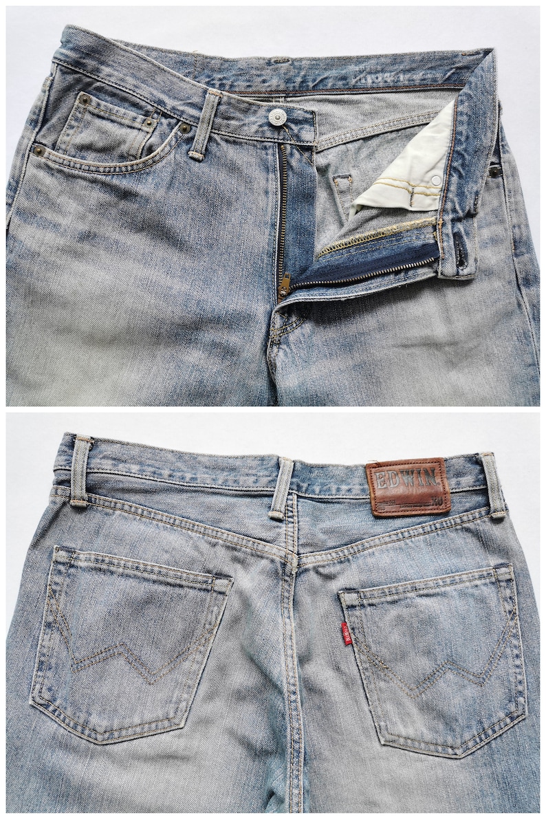May include: Faded light blue denim jeans with a button and zip fly. The jeans feature front and back pockets, belt loops, and a brown leather brand patch. A small red tag is visible on the back pocket.