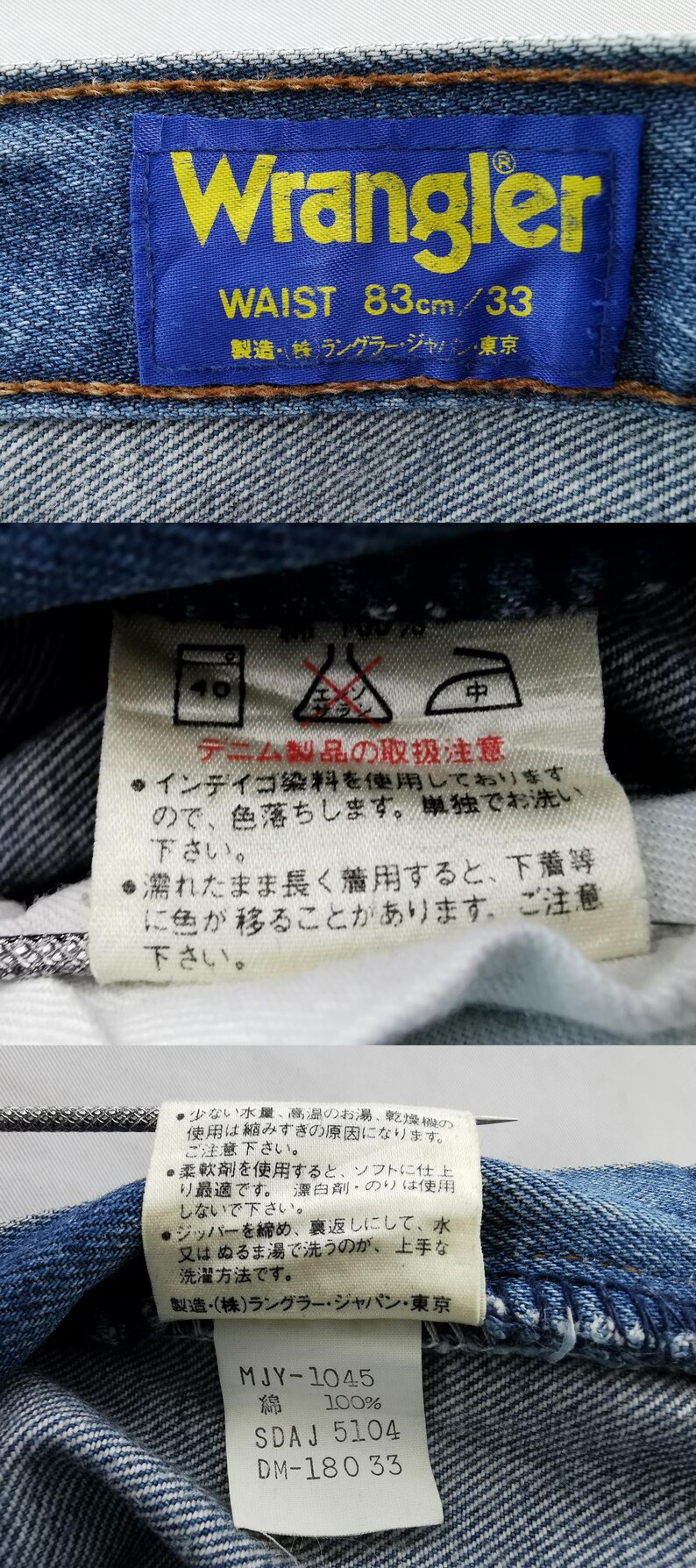 May include: Close-up of a blue denim jeans label with the brand name "Wrangler" in yellow lettering. The label indicates a waist size of 83cm/33. Additional care instructions are printed on a white tag.