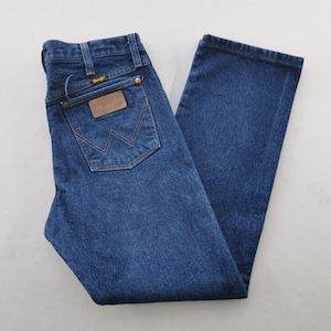 K&ouml;nnte beinhalten: Dunkelblaue Jeans mit klassischer Passform. Die Jeans hat einen braunen Lederaufn&auml;her mit Markenname und Logo auf der Ges&auml;&szlig;tasche. Die Jeans hat ein gerades Bein und einen Knopf- und Rei&szlig;verschluss.