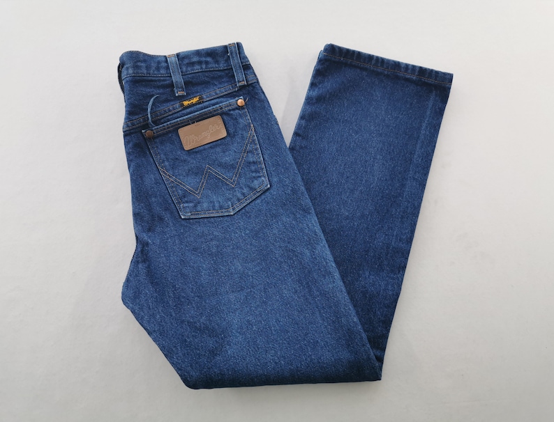 K&ouml;nnte beinhalten: Dunkelblaue Jeans mit klassischer Passform. Die Jeans hat einen braunen Lederaufn&auml;her mit Markenname und Logo auf der Ges&auml;&szlig;tasche. Die Jeans hat ein gerades Bein und einen Knopf- und Rei&szlig;verschluss.
