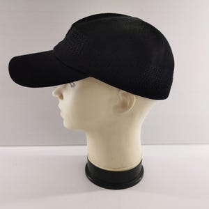 Puede incluir: Gorra de b&eacute;isbol negra con visera curva, exhibida en una cabeza de maniqu&iacute;. La gorra tiene una tela texturizada y transpirable en la corona y una visera s&oacute;lida. El sombrero est&aacute; dise&ntilde;ado para la protecci&oacute;n solar y el uso casual.