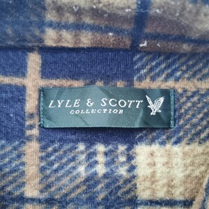Puede incluir: Primer plano de una tela a cuadros azul, marr&oacute;n y beige. Una etiqueta verde oscuro con el texto "LYLE & SCOTT COLLECTION" y un logotipo de &aacute;guila blanca est&aacute; cosida a la tela.