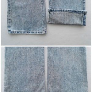 Pu&ograve; includere: Jeans in denim blu chiaro con taglio dritto. Una gamba &egrave; risvoltata, rivelando l'orlo interno. I jeans hanno un classico design a cinque tasche e un lavaggio sbiadito. Gli orli inferiori sono sfilacciati.