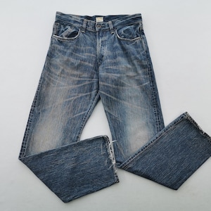 May include: Blue denim jeans with a faded wash and distressed details. The jeans have a classic five-pocket design, a button fly, and a straight leg. The denim is a medium wash with lighter fading.