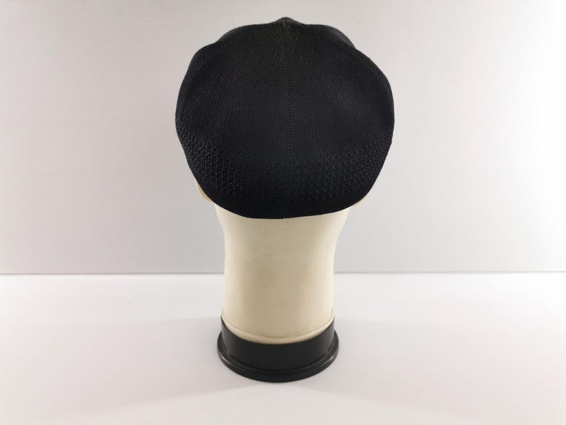Puede incluir: Gorra negra con textura, tipo newsboy, exhibida en una cabeza de maniqu&iacute;. La gorra tiene una corona redondeada y una visera corta y r&iacute;gida. La tela parece ser un material tejido. La cabeza del maniqu&iacute; es blanquecina y la base es negra.