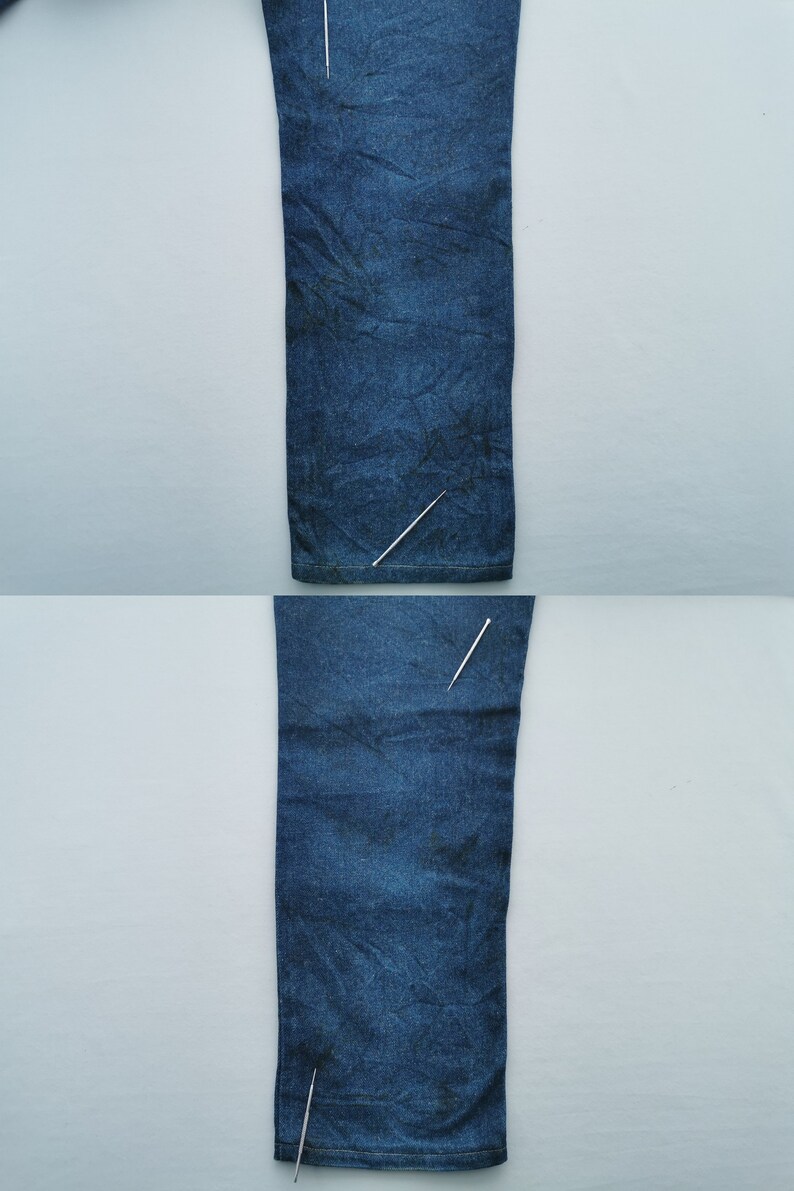 Puede incluir: Dos secciones de vaqueros de mezclilla azul se muestran verticalmente sobre un fondo gris claro. La mezclilla tiene un aspecto ligeramente descolorido con textura y pliegues sutiles. La imagen est&aacute; bien iluminada, destacando los detalles de la tela.