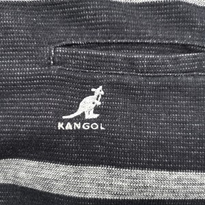 May include: Close-up of a black and gray striped fabric with a pocket. The white embroidered KANGOL logo featuring a kangaroo is visible. The fabric has a textured appearance.