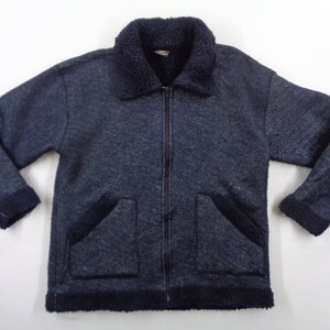 May include: A navy blue zip-up jacket with a dark blue, fuzzy collar and trim. The jacket has two front pockets and a textured appearance. The cuffs and hem are trimmed with the same dark blue, fuzzy material as the collar.