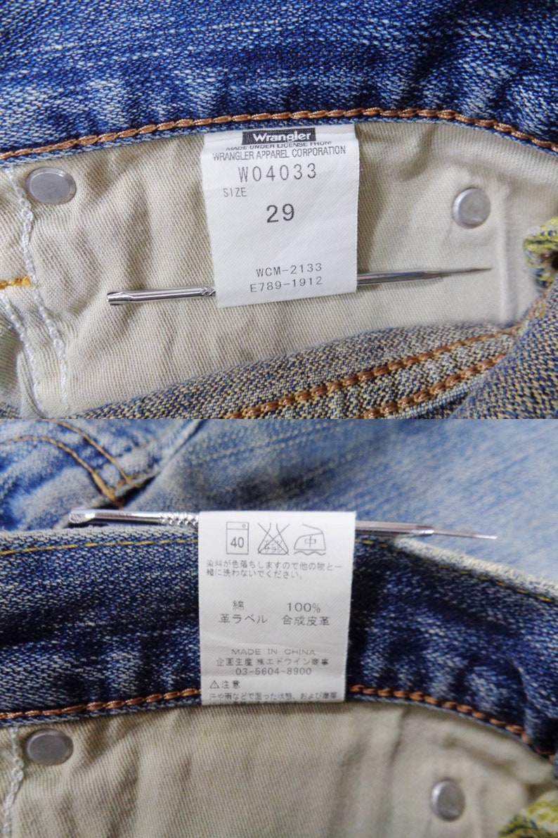 Pu&ograve; includere: Primo piano dell'interno di jeans blu con etichetta "Wrangler", taglia 29, e istruzioni per la cura. I jeans presentano cuciture classiche e indicazioni in giapponese.
