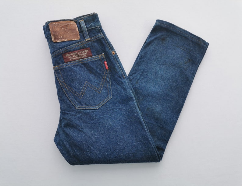 Puede incluir: Vaqueros de mezclilla azul con un dise&ntilde;o cl&aacute;sico de cinco bolsillos. Cuenta con un parche de cuero marr&oacute;n y una etiqueta roja en el bolsillo trasero. Los vaqueros tienen un corte de pierna recta y un lavado descolorido, con costuras visibles y una etiqueta de marca.