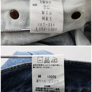 Puede incluir: Primer plano del interior de unos vaqueros azules. La imagen muestra la etiqueta de la marca con el texto "EDWIN 1993" e informaci&oacute;n sobre la talla. Etiquetas adicionales proporcionan instrucciones de cuidado y la composici&oacute;n de la tela.