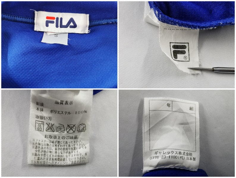 Puede incluir: Primer plano de una chaqueta deportiva azul con detalles blancos. El logotipo de FILA es visible en una etiqueta blanca. Etiquetas adicionales muestran instrucciones de cuidado y texto japon&eacute;s. La chaqueta est&aacute; hecha de 100% poli&eacute;ster.
