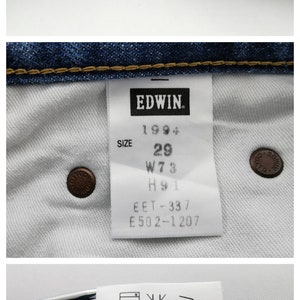 Puede incluir: Primer plano de unos vaqueros de mezclilla azules. La imagen muestra detalles de la tela, las costuras y las etiquetas. Una etiqueta dice "EDWIN 1994" con informaci&oacute;n de talla: 29 cintura, 73 cm. Otra etiqueta proporciona instrucciones de lavado.