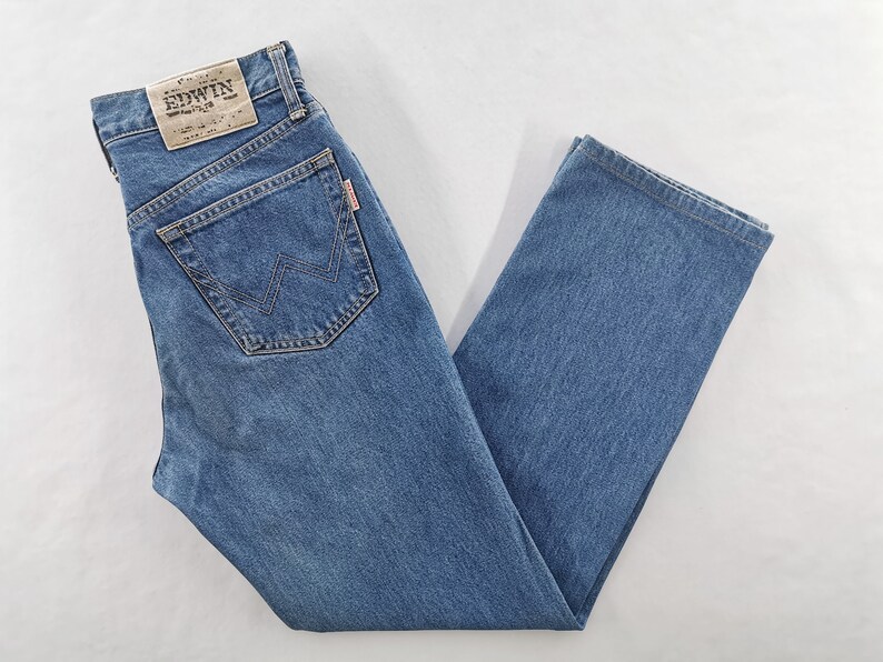 Puede incluir: Vaqueros de mezclilla azules con un dise&ntilde;o cl&aacute;sico de cinco bolsillos. Los vaqueros presentan un corte de pierna recta y un lavado descolorido. El bolsillo trasero tiene una costura distintiva en forma de W. Es visible un parche de cuero con el nombre de la marca.