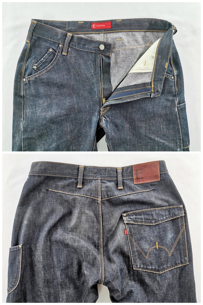 May include: Dark wash denim jeans with a button and zip fastening. Features include front pockets with rivets, a coin pocket, and a back pocket with a distinctive stitch design. The brand name "E FUNCTION" is visible on a red tag.