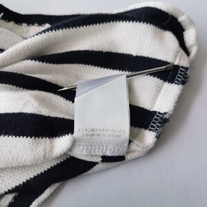 Puede incluir: Primer plano de una tela a rayas blancas y azul marino. La tela est&aacute; doblada, con una etiqueta sujeta con un alfiler. La etiqueta tiene texto japon&eacute;s. La tela parece ser de punto.