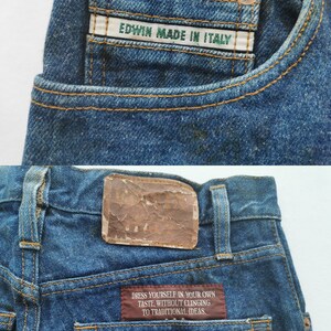 Puede incluir: Primer plano de unos vaqueros azules con costuras visibles y remaches de cobre. Los vaqueros tienen una etiqueta en el bolsillo que dice "EDWIN MADE IN ITALY". El bolsillo trasero tiene una etiqueta con el texto "DRESS YOURSELF IN YOUR OWN TASTE, WITHOUT CLINGING TO TRADITIONAL IDEAS."