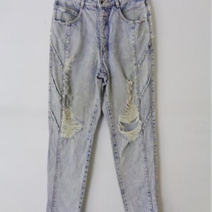 May include: Light blue acid wash jeans with distressed details. The jeans have a high waist, a button and zipper closure, and pockets. The denim pants are hanging on a hanger against a white background.