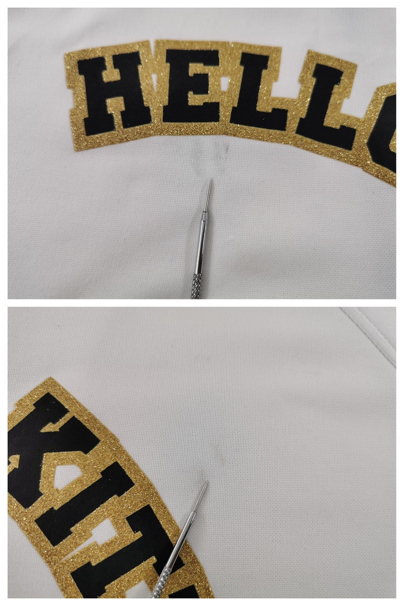 May include: Close-up of a white fabric with the word "HELLO KITTY" in black letters with gold glitter trim. A silver tool is in the image.