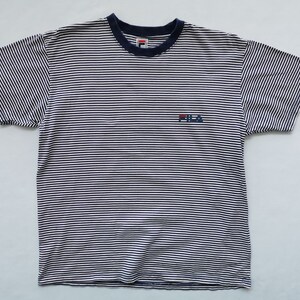 Puede incluir: Camiseta a rayas blancas y azul marino con cuello azul marino y el logo de Fila bordado en el pecho. La camiseta de manga corta tiene un dise&ntilde;o cl&aacute;sico e informal.