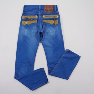 K&ouml;nnte beinhalten: Blaue Jeans mit einzigartigen Designelementen. Sie verf&uuml;gen &uuml;ber beige Wildleder-Akzente, Rei&szlig;verschlusstaschen und einen Lederaufn&auml;her am Bund. Die Jeans haben ein klassisches F&uuml;nf-Taschen-Design und eine mittlere Waschung.
