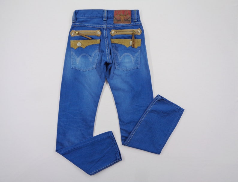 K&ouml;nnte beinhalten: Blaue Jeans mit einzigartigen Designelementen. Sie verf&uuml;gen &uuml;ber beige Wildleder-Akzente, Rei&szlig;verschlusstaschen und einen Lederaufn&auml;her am Bund. Die Jeans haben ein klassisches F&uuml;nf-Taschen-Design und eine mittlere Waschung.