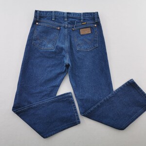 K&ouml;nnte beinhalten: Blaue Jeans aus Denim mit klassischem F&uuml;nf-Taschen-Design. Die Jeans haben Kupfernieten, einen braunen Lederaufn&auml;her und das Wrangler-Logo. Die Jeans sind im Straight-Leg-Stil.
