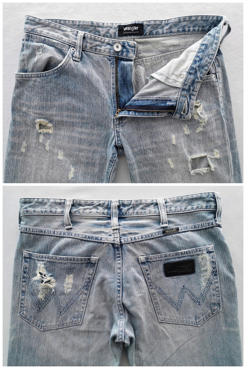 Pu&ograve; includere: Jeans in denim blu chiaro con dettagli strappati, tra cui aree strappate. I jeans hanno una chiusura con bottone e cerniera, tasche anteriori e posteriori, e l'etichetta del marchio "Wrangler" &egrave; visibile. Stile classico.